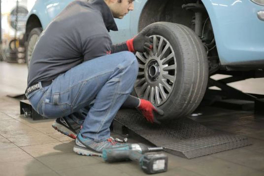 A man performing a tire fitting at home, ensuring the proper installation of a car tire.