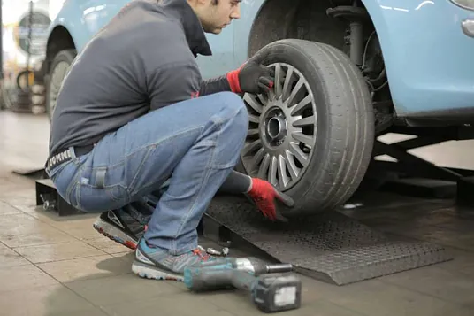 A man performing a tire fitting at home, ensuring the proper installation of a car tire.